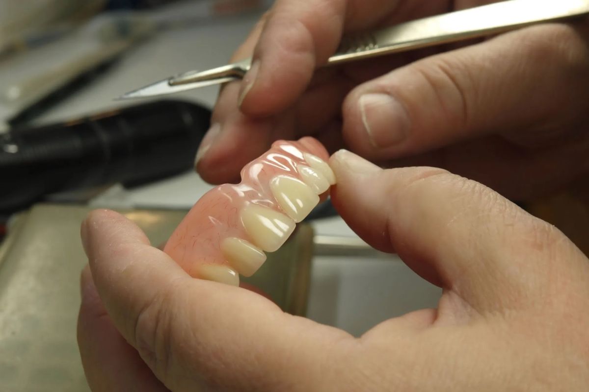 hand holding denture undergoing dental repair