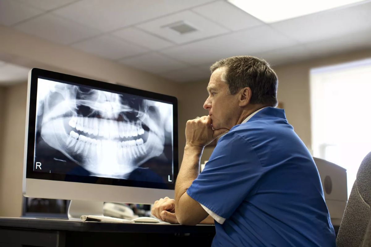 a dentist reviewing a dental X-ray on a computer monitor