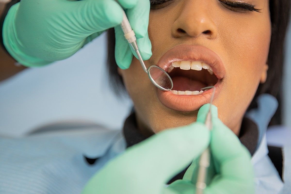 female patient receiving an oral examination as a dentist checks her teeth with professional tools