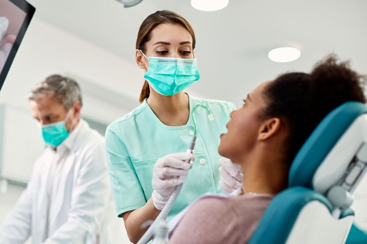 dentist performing oral health assessment on a female patient