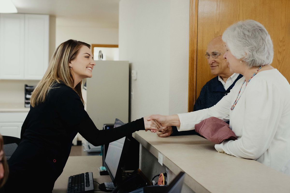 friendly receptionist welcoming walk-in patients at the dental office lobby