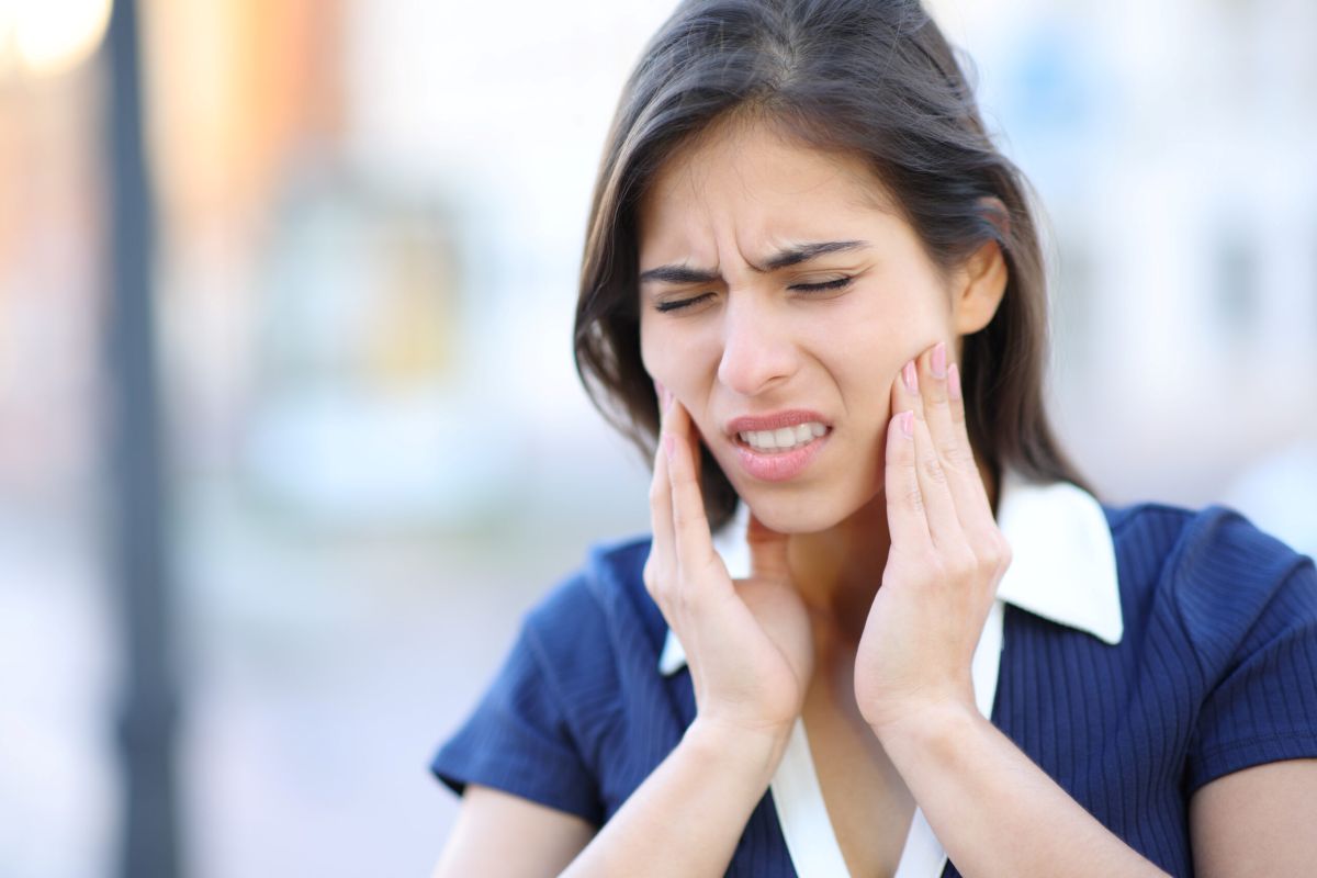 woman holding cheeks in tooth pain discomfort