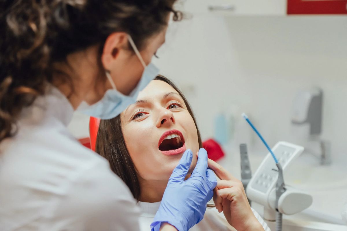 patient with mouth open sitting in dental chair while dentist explains dental treatment