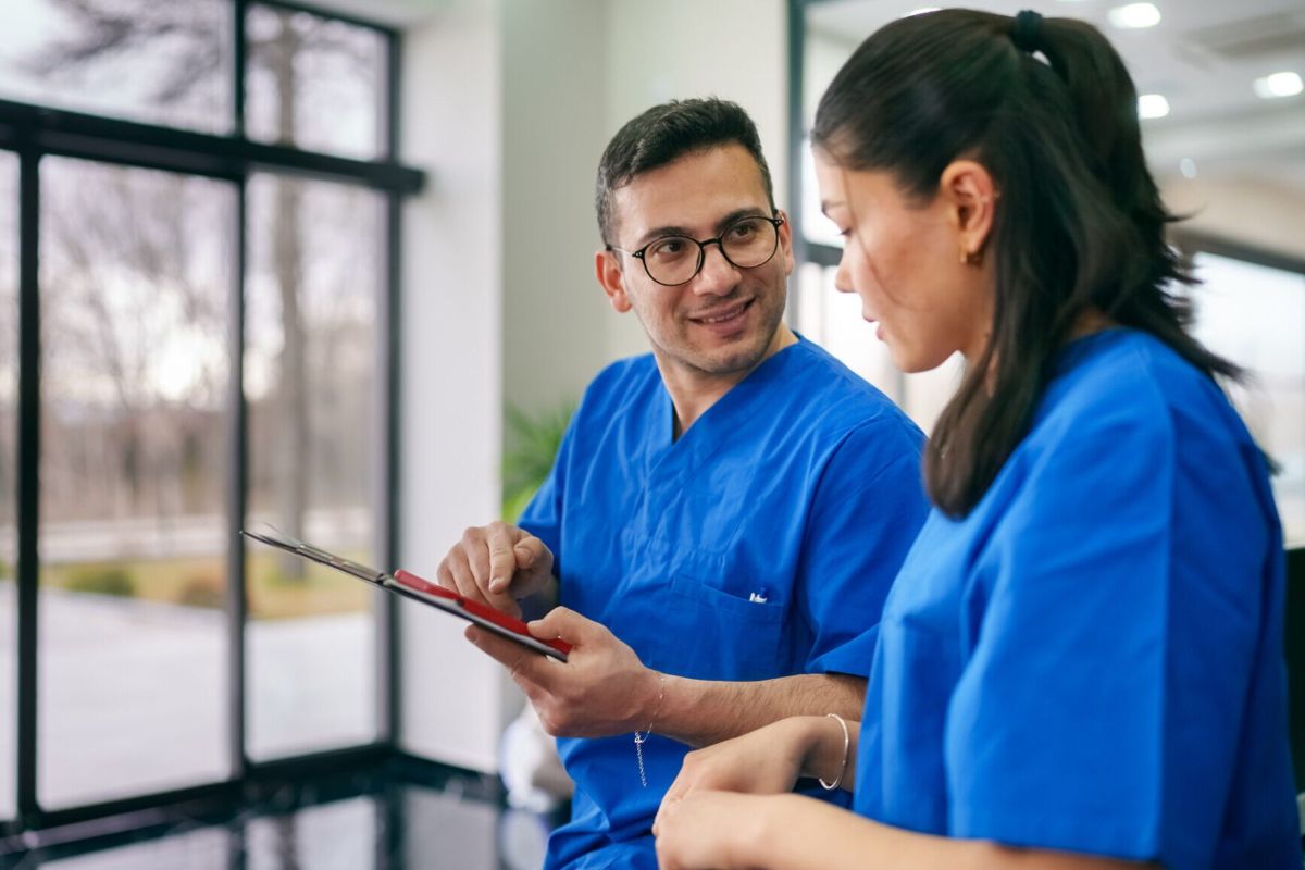 dentists wearing blue scrub uniforms having a conversation in corridor